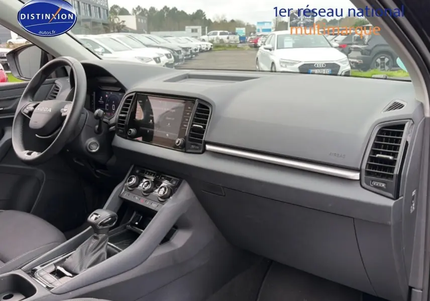 Intérieur noir du Skoda Karoq 2025, vue de profil côté conducteur sur tableau de bord et console centrale.