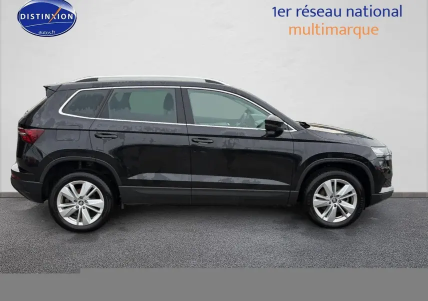 Vue de profil côté gauche d'un Skoda Karoq noir 2025 avec jantes alliage et barres de toit argentées.