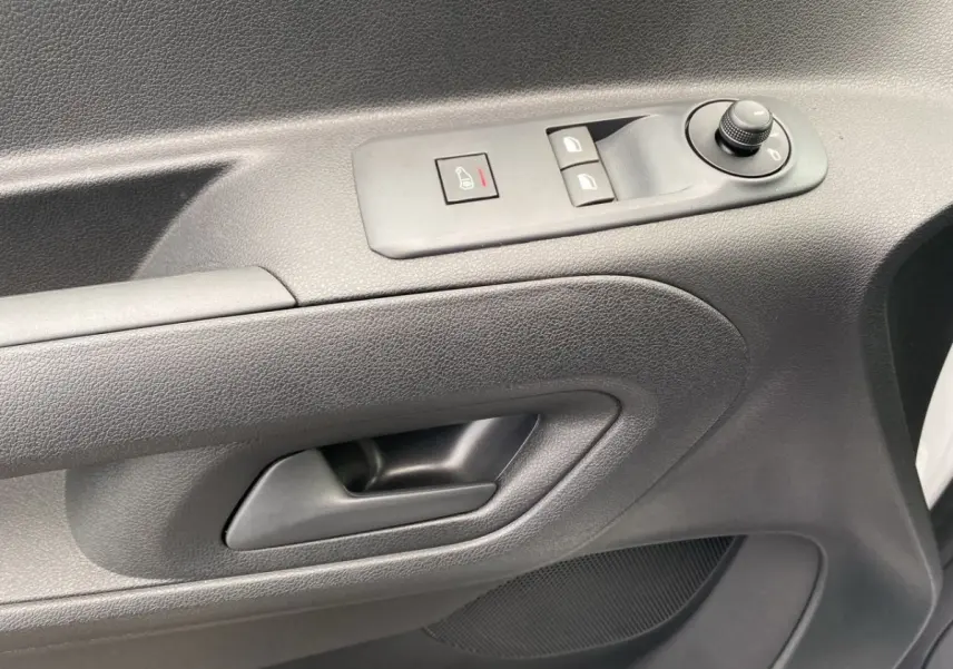 Gros plan sur la porte intérieure côté conducteur du Peugeot Partner blanc, avec commandes de vitres et rétroviseurs.