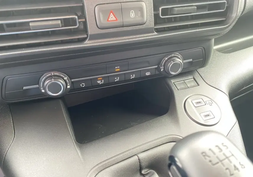 Vue rapprochée de la console centrale noire du Peugeot Partner 2024 avec commandes climatisation et levier de vitesses manuel.