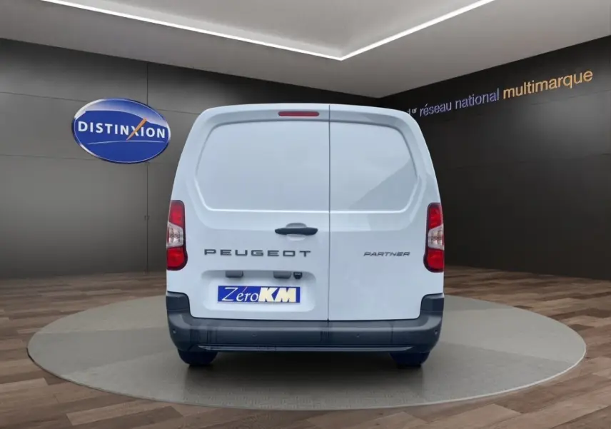 Vue arrière d’un utilitaire blanc Peugeot Partner 2024 sur plateau tournant en showroom.