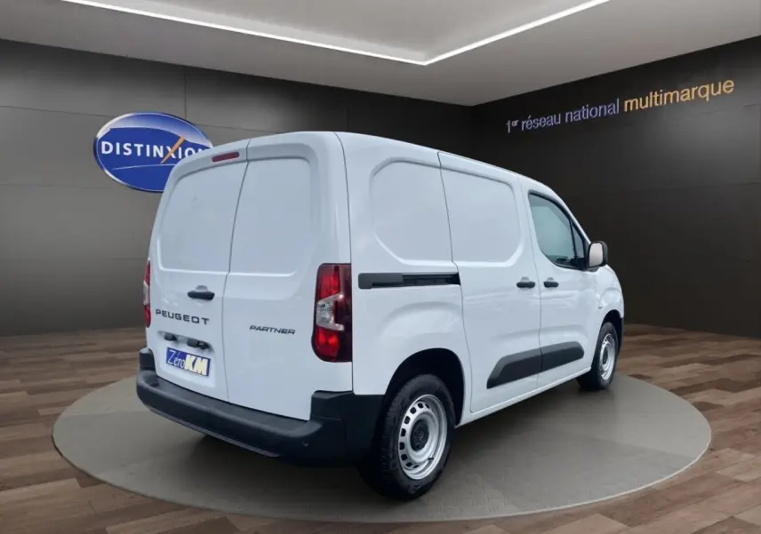 Vue 3/4 arrière droite du Peugeot Partner blanc utilitaire avec portes arrière battantes et protections noires latérales.