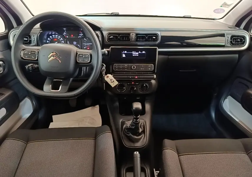 Vue intérieure avant de la Citroën C3 blanche de 2019, montrant le tableau de bord et la boîte manuelle.