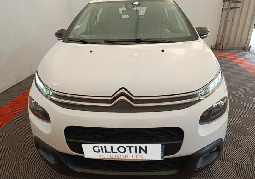 Vue avant d'une Citroën C3 blanche de 2019 avec calandre noire et phares LED allumés en intérieur.