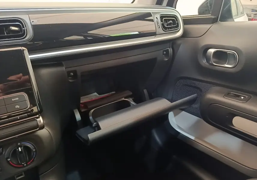 Intérieur de la Citroën C3 blanc, vue côté passager sur la boîte à gants ouverte et tableau de bord noir brillant.