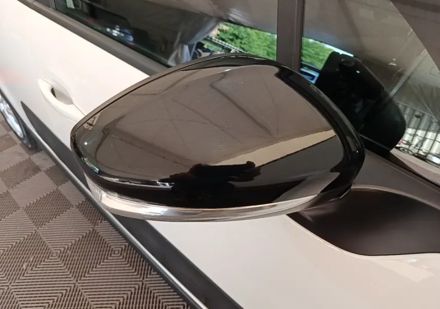 Gros plan sur le rétroviseur noir brillant côté gauche d'une Citroën C3 blanche vue de profil.