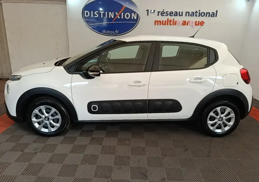 Profil droit d'une Citroën C3 blanche 2019 avec protections latérales noires et jantes argentées en intérieur showroom.