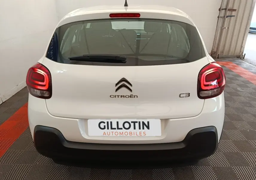 Vue arrière d'une Citroën C3 blanche de 2019 avec feux arrière allumés et pare-chocs noir dans un garage.