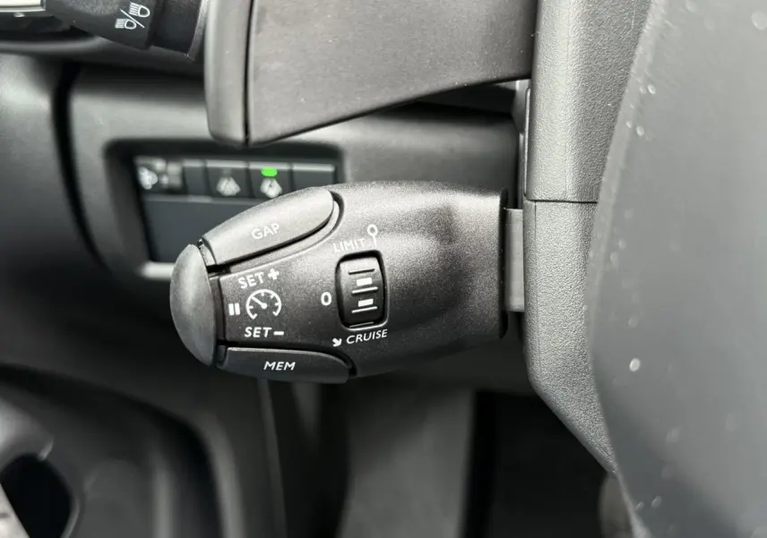 Gros plan sur la commande de régulateur de vitesse au volant d'une Citroën C5 Aircross Hybrid noir intérieur.