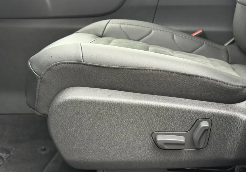 Gros plan sur le siège conducteur noir Alcantara et tissu effet cuir du Citroën C5 Aircross Hybrid 2025, avec commandes électriques visibles.