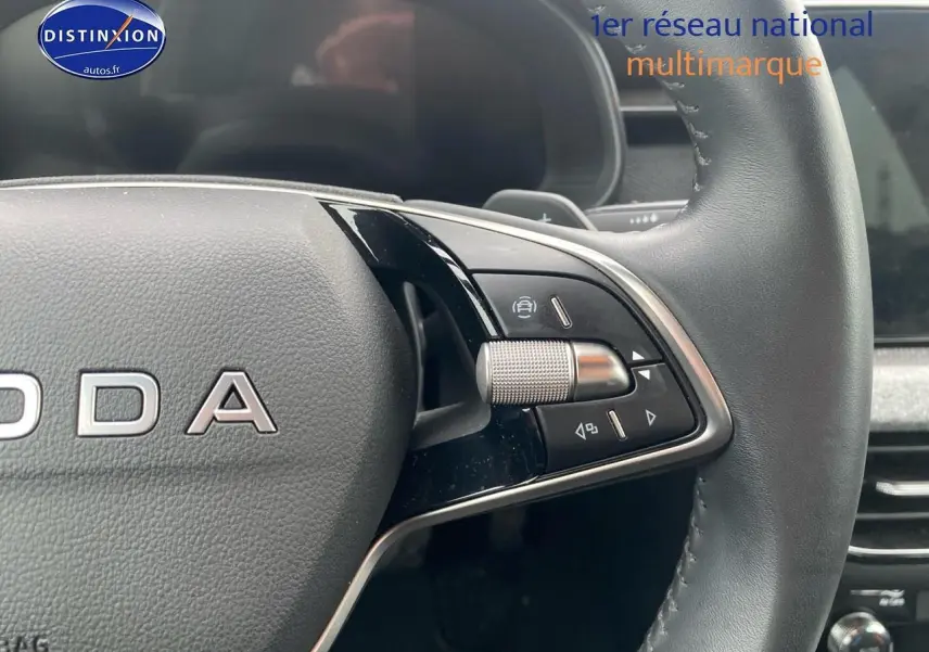 Gros plan sur le volant cuir noir du Skoda Kamiq 2025, avec commandes multifonctions et molette argentée à droite.