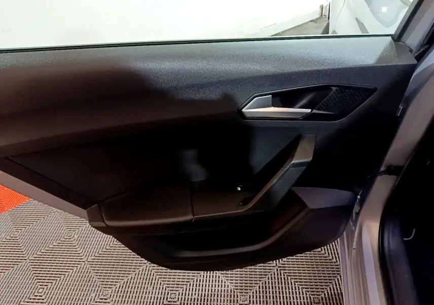 Vue intérieure de la porte avant droite d'une SEAT Leon gris foncé avec poignée argentée et panneau noir épuré.