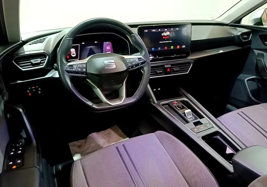 Vue intérieure avant droite du tableau de bord et volant cuir alu de la SEAT Leon gris foncé avec écran tactile central.