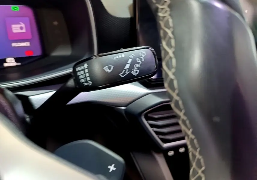 Gros plan sur la commande des essuie-glaces du SEAT Leon 2022, intérieur noir avec volant en cuir surpiqué.