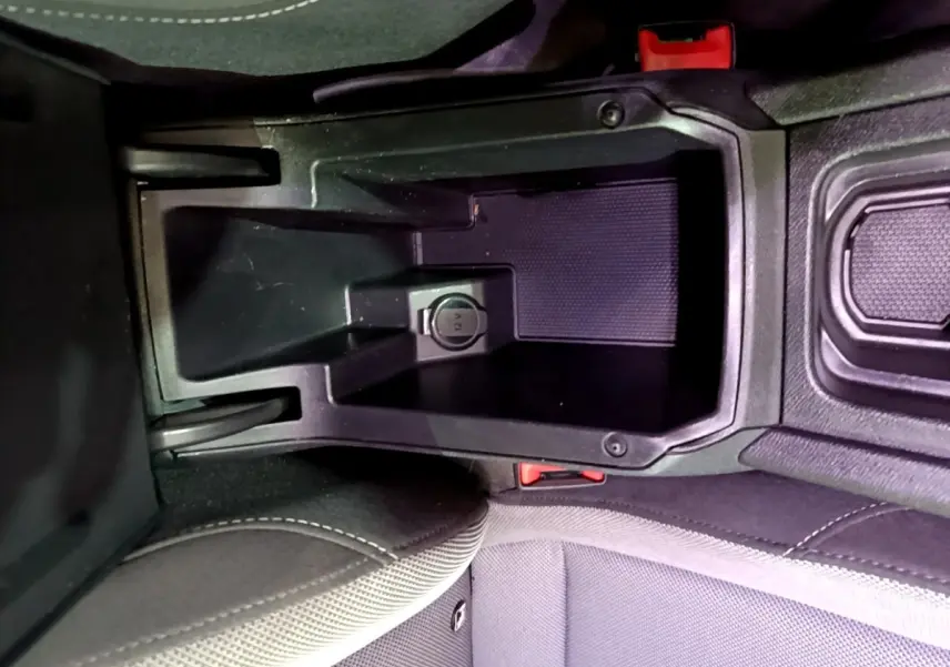 Vue rapprochée de la console centrale intérieure du SEAT Leon gris foncé, montrant la prise 12V et les sièges tissu.