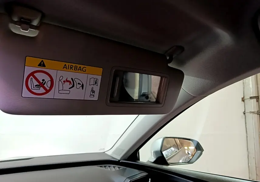 Vue intérieure côté passager de la SEAT Leon gris foncé 2022, avec pare-soleil rabattu et miroir de courtoisie visible.