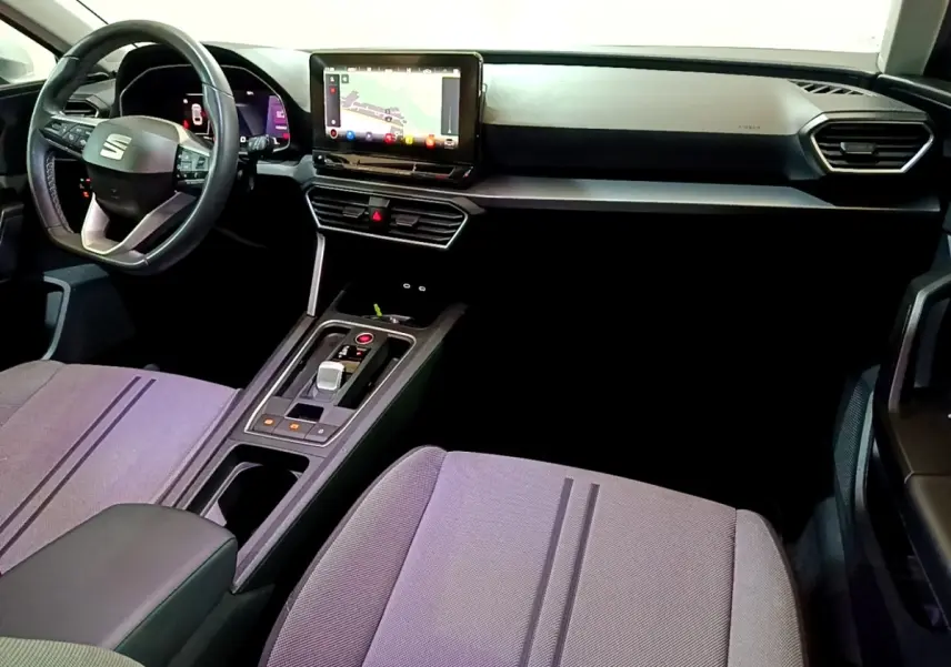 Intérieur avant du SEAT Leon 2022, vue côté conducteur, tableau de bord noir avec écran tactile et volant cuir.