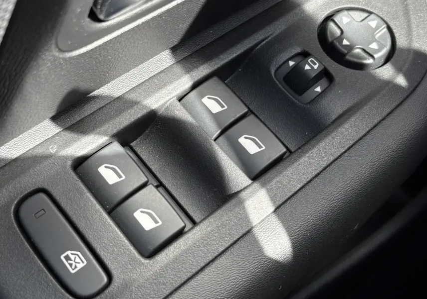 Gros plan sur les commandes de lève-vitres et réglage des rétroviseurs côté conducteur d’une Citroën C4 Hybrid 2025.