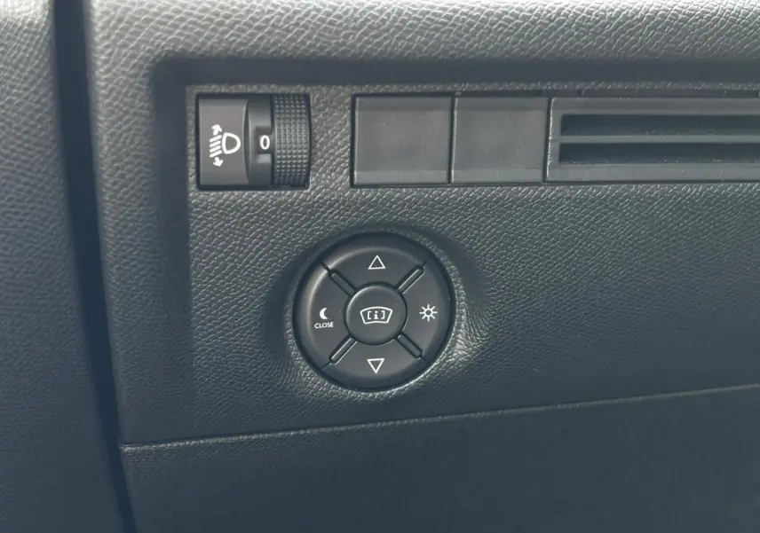 Gros plan sur les commandes d’éclairage et réglage du tableau de bord noir dans une Citroën C4 Hybrid 2025 Bleu Eclipse.
