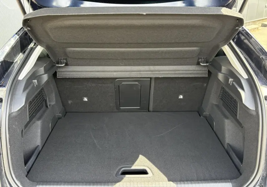 Coffre ouvert vu de l'arrière d'une Citroën C4 Hybrid 145 bleu Eclipse, espace de chargement vide et tapis noir.