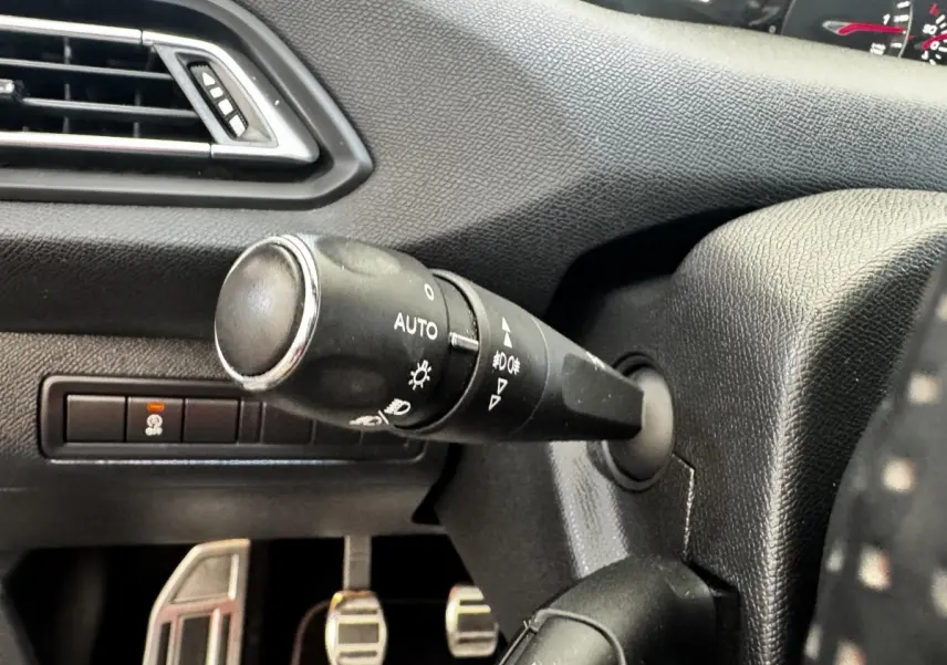 Gros plan sur la manette de commande des phares à gauche du volant dans l’habitacle noir du Peugeot 308 GT Line 2018.