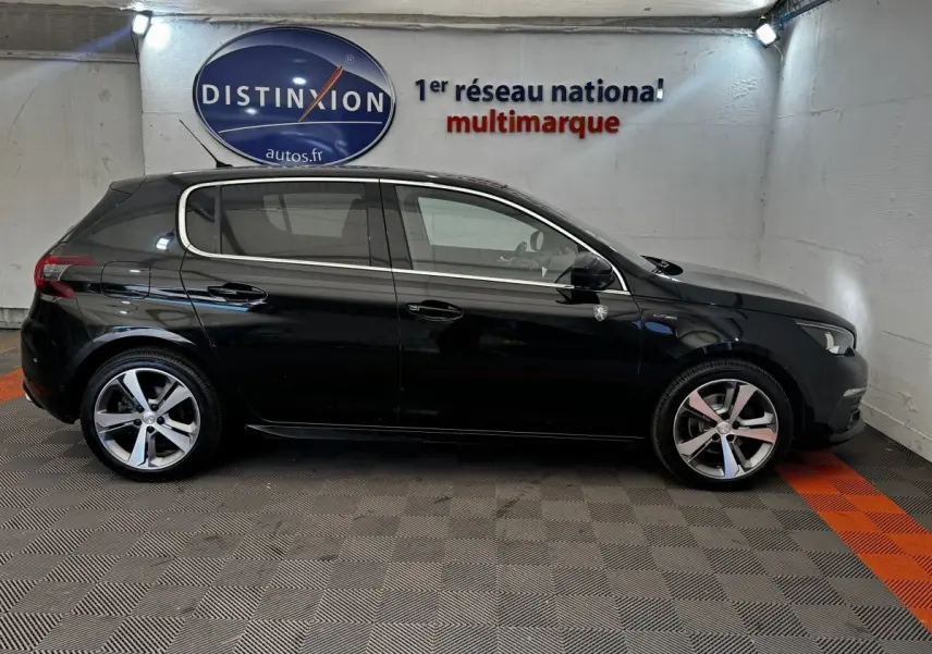 Peugeot 308 GT Line noire vue de profil côté gauche dans un garage avec sol gris et orange.