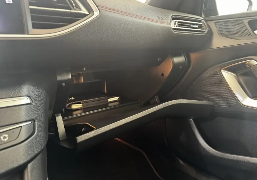 Vue intérieure côté passager de la Peugeot 308 GT Line 2018, boîte à gants ouverte avec éclairage ambiant rouge.
