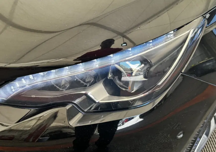 Gros plan sur le phare avant droit noir brillant de la Peugeot 308 1.5 BlueHDi 130 S&S GT Line 2018.