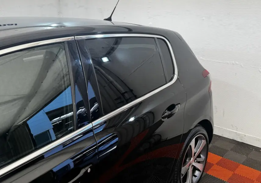 Vue côté droit arrière d’une Peugeot 308 noire 2018 avec jantes alliage et vitres teintées.