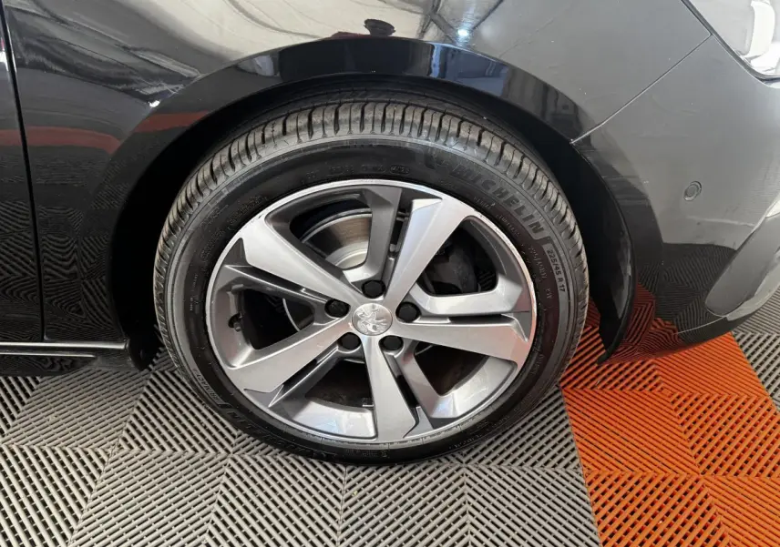Gros plan sur la roue avant droite de la Peugeot 308 noire, avec jante alliage cinq branches et pneu Michelin.