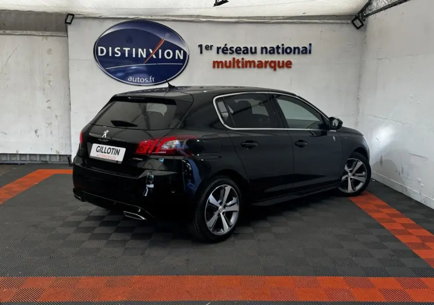 Peugeot 308 noire vue 3/4 arrière droit dans un garage avec jantes alliage et feux LED distinctifs.