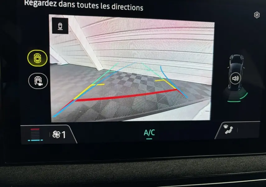 Affichage de la caméra de recul de la Renault Clio blanche 2026 avec lignes de guidage colorées et vue intérieure du tableau de bord.