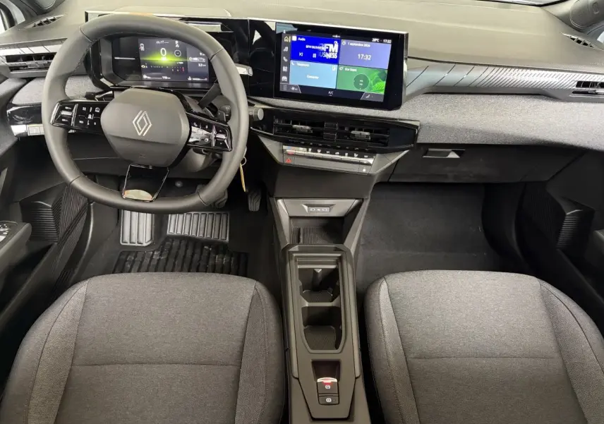 Vue intérieure frontale du tableau de bord de la Renault Clio blanche 2026 avec écran tactile et volant multifonction.