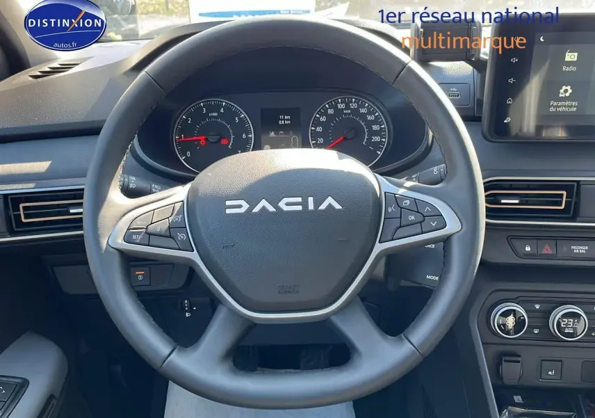 Vue rapprochée du volant multifonction DACIA Sandero 2025 avec tableau de bord et écran tactile visibles.