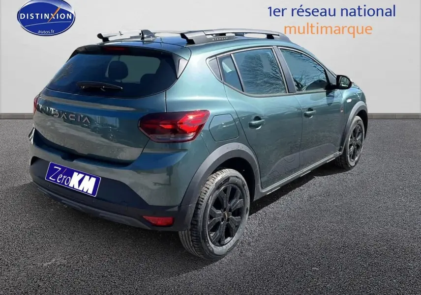 Vue 3/4 arrière droite d'une Dacia Sandero Stepway 2025 vert cèdre avec barres de toit et jantes noires.