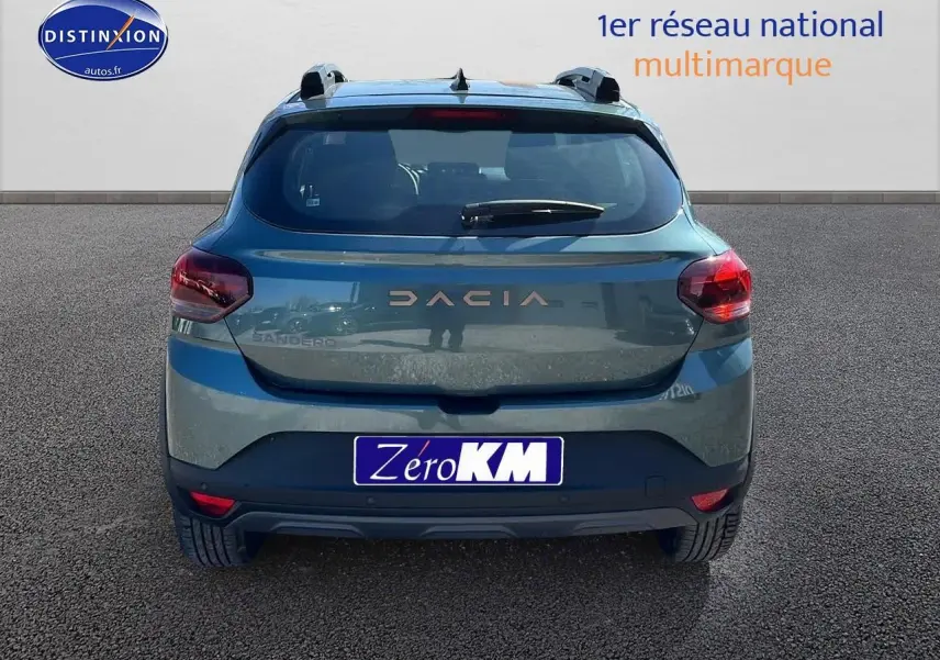 Vue arrière d'une Dacia Sandero 2025 vert cèdre avec barres de toit et becquet arrière.