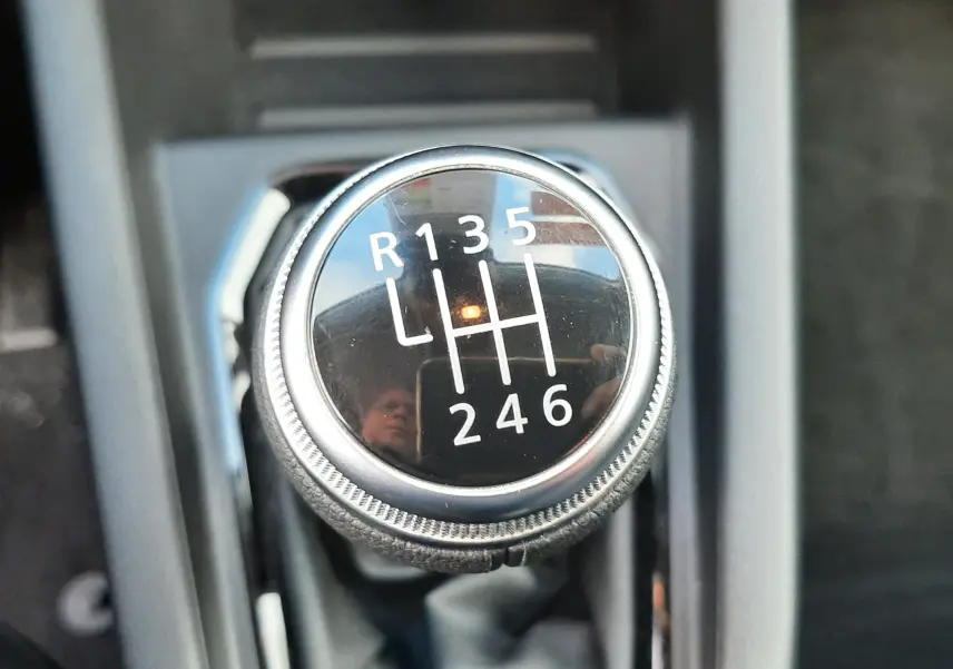 Gros plan sur le levier de vitesses manuel noir de la Renault Clio V blanche, montrant les six rapports et la marche arrière.