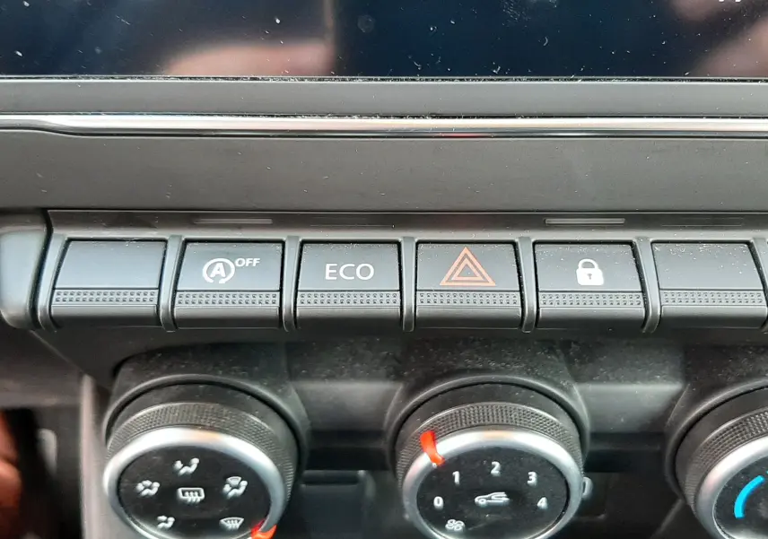 Gros plan sur la console centrale noire de la Renault Clio V 2022, montrant les boutons de contrôle et les réglages de climatisation.