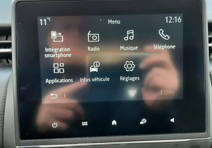 Écran tactile central de la Renault Clio V blanc, affichant le menu principal avec options smartphone, radio, musique et téléphone.