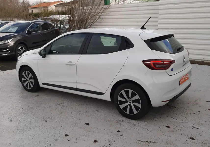 Renault Clio V blanche vue de côté droit en extérieur, avec jantes alliage et vitres teintées arrière.