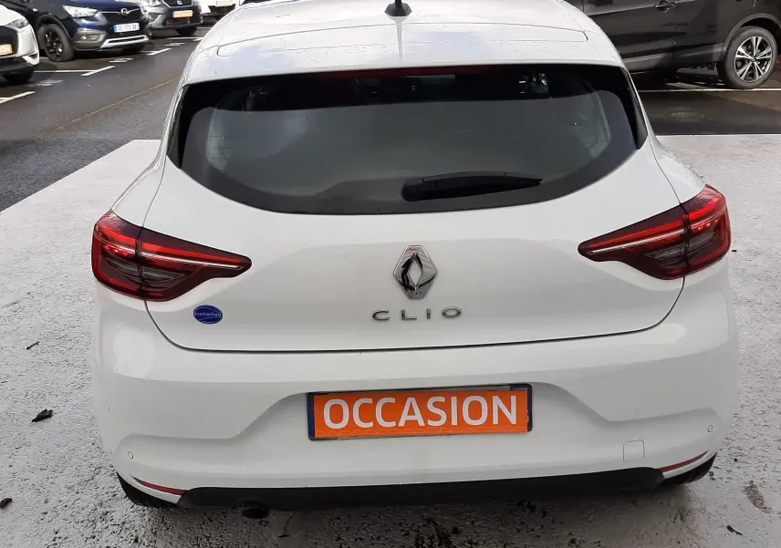 Vue arrière d'une Renault Clio V blanche de 2022 avec plaque "OCCASION" visible sur un parking extérieur.