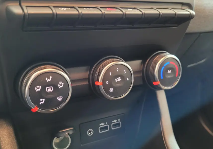 Gros plan sur les commandes de climatisation et les ports USB du tableau de bord de la Renault Clio bleu 2025.