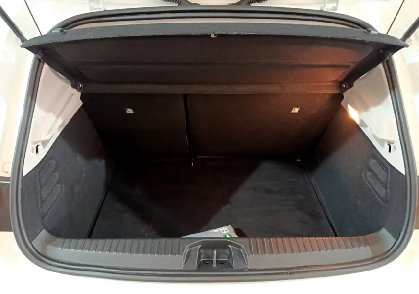 Coffre ouvert vu de face d'une Renault Clio Business blanche, montrant l'espace de chargement vide et l'éclairage intérieur.