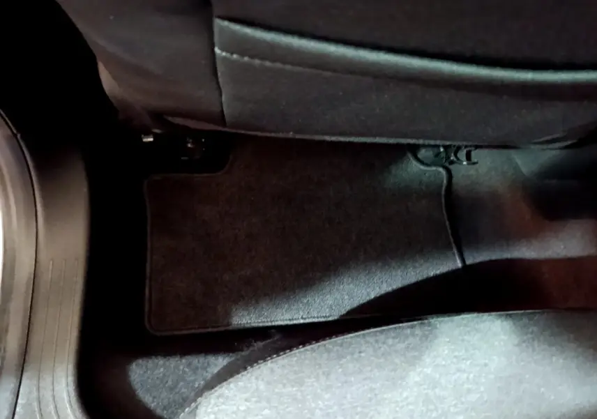 Vue rapprochée du tapis de sol noir situé au sol côté arrière d’une Renault Clio Business blanche de 2021.