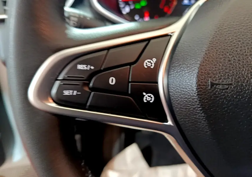 Gros plan sur les commandes au volant côté gauche d'une Renault Clio Business blanche, avec boutons de régulateur de vitesse.