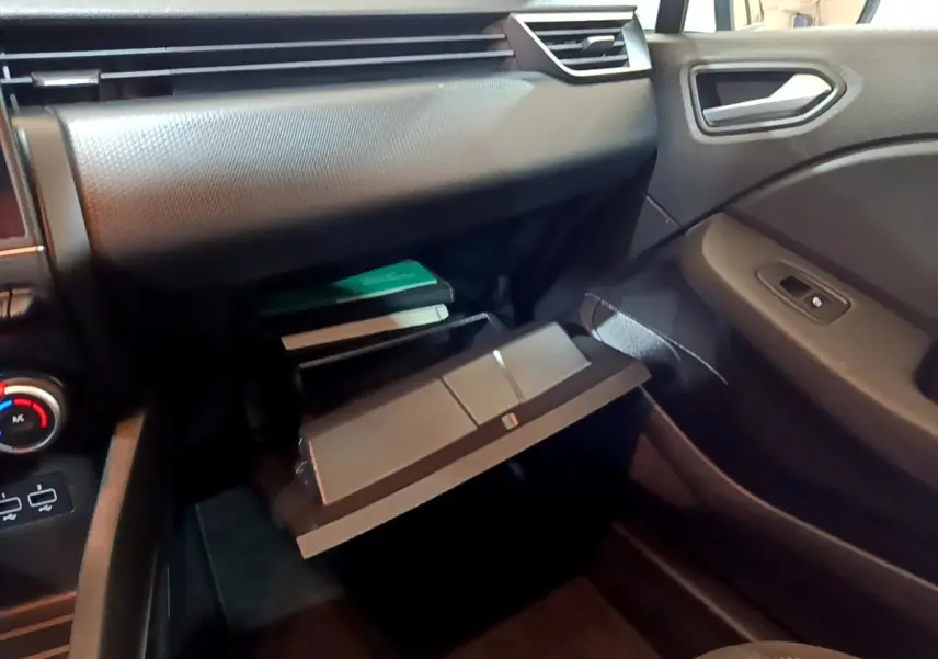 Intérieur de la Renault Clio Business blanc, vue côté passager sur la boîte à gants ouverte et tableau de bord noir.