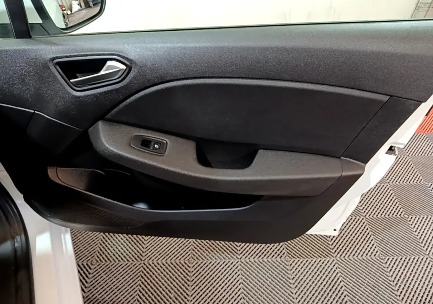 Intérieur de la porte avant gauche d'une Renault Clio Business blanche, avec poignée et commande de vitre noire.
