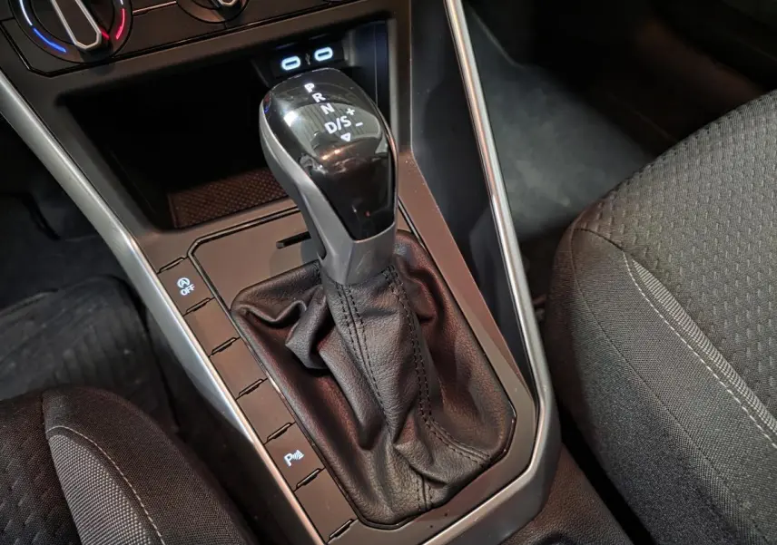 Le levier de vitesses automatique noir et argenté de la Volkswagen Polo 2025, avec sellerie tissu grise visible à droite.