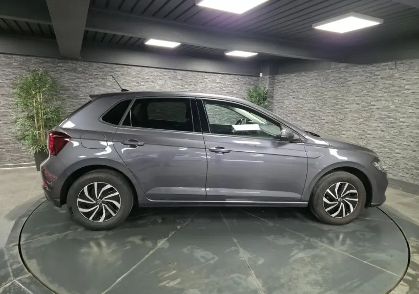 Volkswagen Polo gris métallisé vue de profil côté gauche avec jantes alliage et antenne de toit.