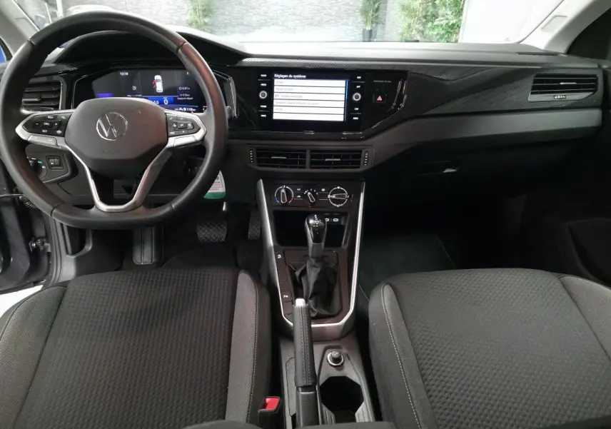 Vue intérieure avant de la Volkswagen Polo 2025 gris, tableau de bord avec écran tactile et volant cuir multifonction.